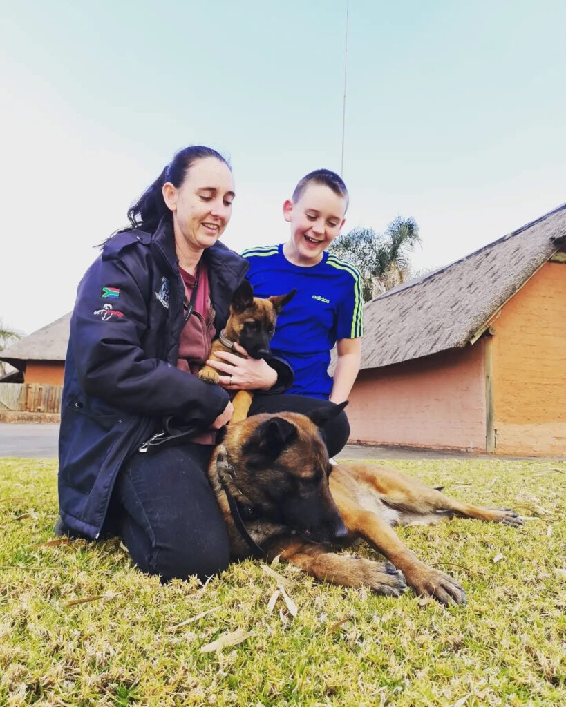 Marilé with a puppy and an adult dog, raised at home with the family